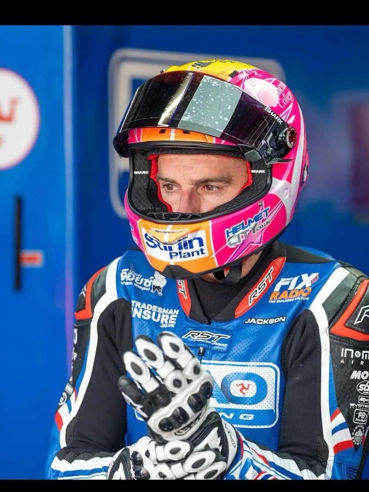 British Superbikes rider in a pink helmet and TradesmanInsure-sponsored leathers in the pit garage